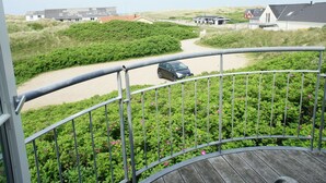 Un balcon donnant sur une route côtière et sur des maisons.