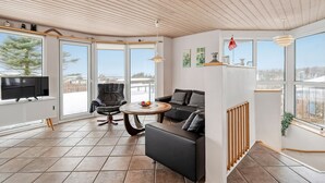 Un salón amplio con un gran ventanal, chimenea y un cómodo conjunto de asientos.