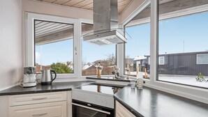 Una cocina moderna con un amplio ventanal, horno empotrado y cafetera.