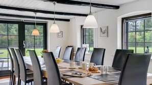 A dining area with a wooden table, black chairs, and hanging pendant lights.