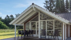 A covered outdoor area with a wooden deck, a dining table with chairs, and large windows. - "Lisel" - 25km from the sea by Interhome (Toftlund)