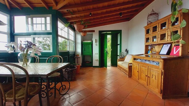 Une cuisine spacieuse avec des meubles de rangement en bois, une table à manger avec des chaises et une porte verte donnant sur l’extérieur.