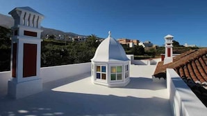 Une terrasse sur le toit dotée d’une structure en forme de dôme blanc, de murs blancs et de touches de couleur rouge.