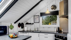 A modern kitchen with white cabinetry, a black countertop, a built-in oven, and a window with a view of greenery outside. - "Liljana" - 30km from the sea by Interhome (Toftlund)