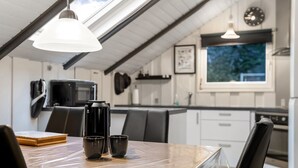 A modern kitchen with a dining area, featuring a table with a coffee maker, cups, and a book. - "Liljana" - 30km from the sea by Interhome (Toftlund)
