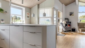 A modern kitchen with white cabinetry, pendant lighting, and a view to the outdoors.