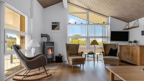 A modern living room with a fireplace, comfortable seating, and large windows.