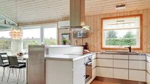Et moderne køkken med træpaneler, et stort vindue og et spiseområde med et bord og stole.
