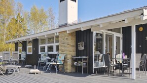 A wooden deck with outdoor seating, a brick wall, and a covered area with tables and chairs. - "Alvine" - 475m from the sea by Interhome (Jerup)