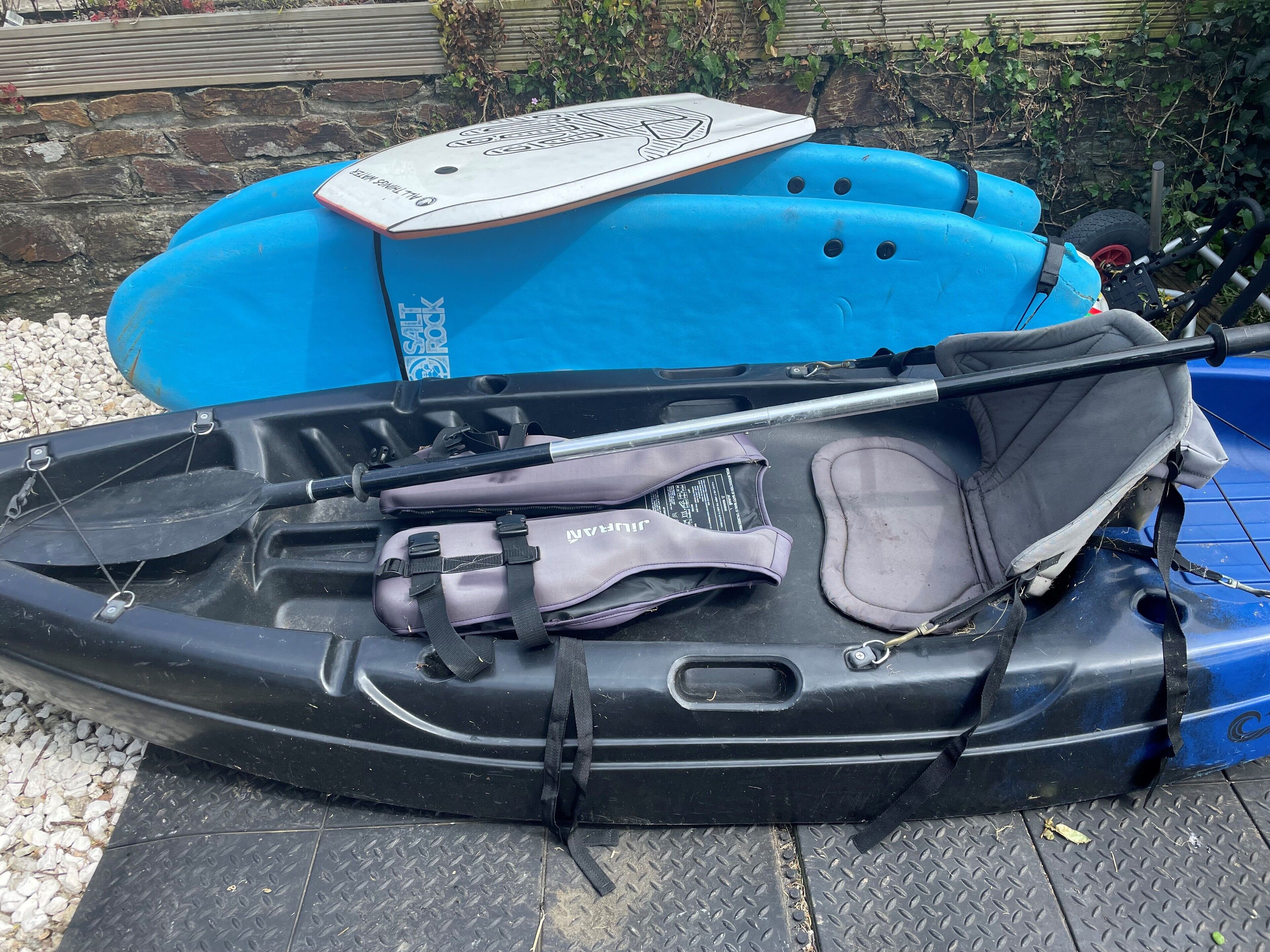 Un kayak avec une pagaie, un gilet de sauvetage et un casque rangés dans une boîte bleue.