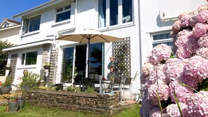 Una casa de dos pisos con un patio, una mesa de comedor y sillas.