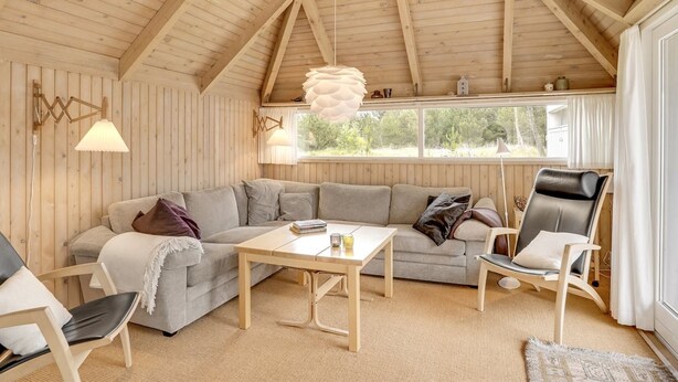 L’intérieur d’un chalet chaleureux, avec un plafond en bois, un canapé, une table et une chaise.