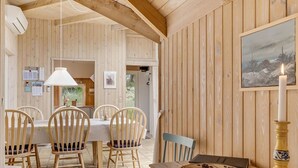 Un intérieur en bois avec une table à manger, des chaises, une bougie et un tableau encadré au mur.
