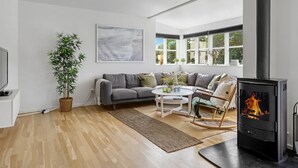 Un salon moderne avec un canapé, une table basse, une cheminée et une grande fenêtre.