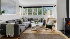 Un salon moderne avec un canapé d’angle, une table basse ronde et une cheminée.