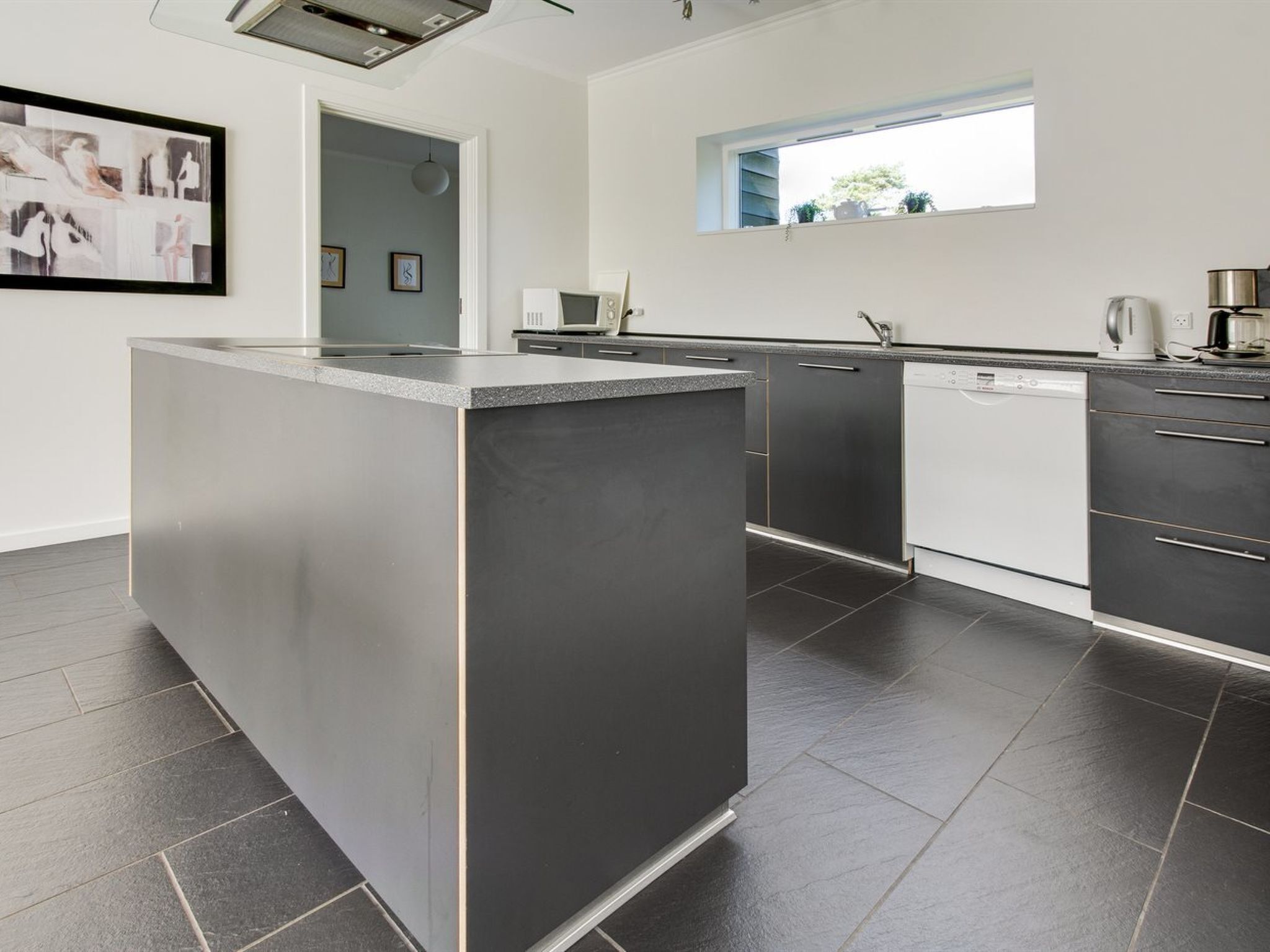 A modern kitchen with a central island, white cabinetry, and a window above the sink.