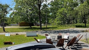 A hot tub with a view of a grassy area and trees in the background. - Walk to breweries, restaurants, and shops from this charming cottage featuring a private hot tub, comfortable living spaces, and easy access to Nelson 151, wineries, hiking trails, and the Blue Ridge. (Nellysford)