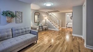 Ein Wohnzimmer mit einer Couch, Stühlen, einem kleinen Tisch, einer Treppe und einem Schlafzimmer mit einem Bett.