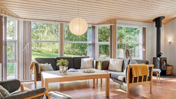 A cozy living room with a sofa, chairs, a wooden coffee table, and a large window overlooking a garden. - "Barne" - 4km from the sea by Interhome (Sæby)