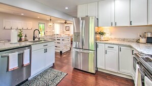 A modern kitchen with white cabinets, stainless steel appliances, and a patterned rug. - Relax at a peaceful farmhouse near Nelson 151 featuring three king bedrooms, a brand-new private hot tub, fire pit, and inviting gathering spaces—just minutes from wineries, breweries, hiking, and Blue Ridge adventures. (Afton)
