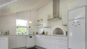 Una cocina moderna con armarios blancos, horno empotrado y refrigerador.