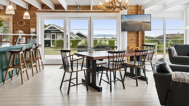 A spacious kitchen with a large island, a dining area with a wooden table and chairs, and a living area with a sofa and a TV mounted on the wall.