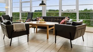 A spacious room with a large window, a black leather sofa, and a wooden coffee table.