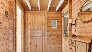 A wooden hallway with a door, a framed sign, and a mirror on the wall.