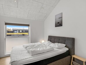 Une chambre à coucher avec un lit, une fenêtre, une tête de lit et une petite table.
