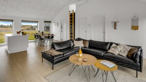 A spacious living area with a black leather sofa, a wooden coffee table, and a white island. - "Tatiane" - 1.5km from the sea by Interhome (Løkken)