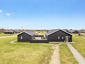 Une rangée de cabanes en bois sombre, avec un chemin pavé devant.