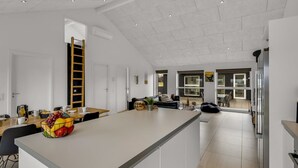 A modern kitchen with a central island, white cabinetry, and a dining area with chairs and a table. - "Tatiane" - 1.5km from the sea by Interhome (Løkken)