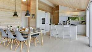 Eine moderne Küche mit weißen Schränken, einer Holzbalkendecke und einer zentralen Kochinsel mit Barhocker.