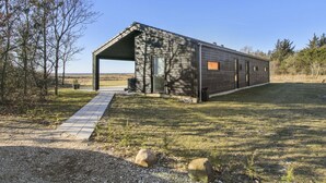 Ein modernes, eingeschossiges Gebäude mit einer überdachten Veranda und freiem Blick auf die umliegende Landschaft.