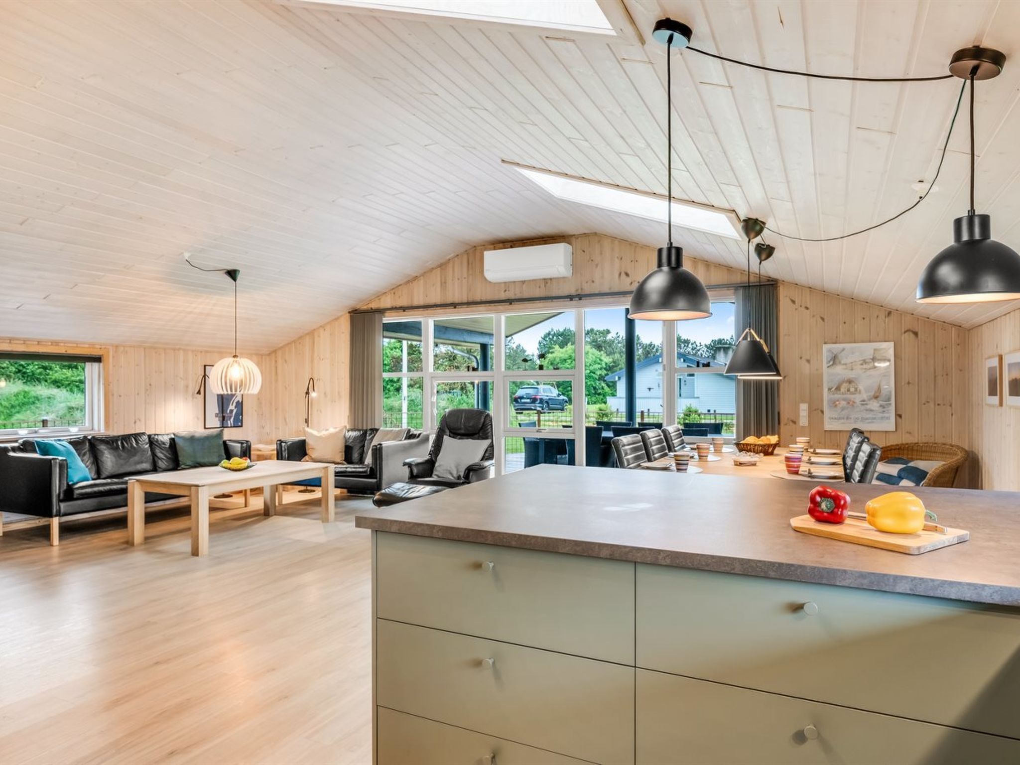 Une cuisine moderne dotée d’un grand îlot central, d’un plafond en bois et de grandes fenêtres.