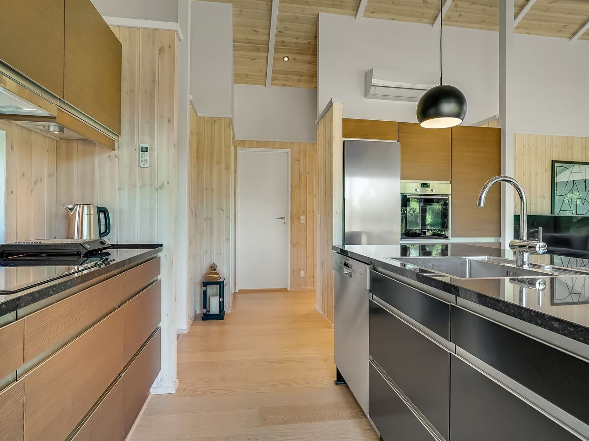 Una cocina moderna con armarios de madera, un refrigerador de acero inoxidable y una encimera negra.