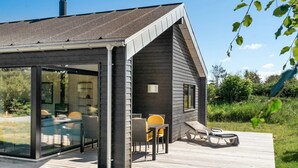 A modern house with a deck, large glass windows, and outdoor seating.