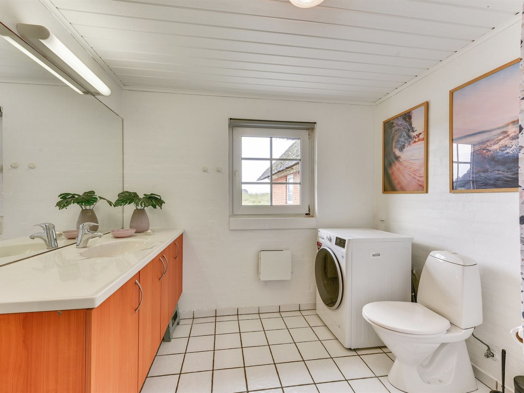 Ein kleines Badezimmer mit einem weißen Waschbecken, einem Holzwaschtisch, einer Waschmaschine und einer Toilette.