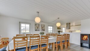 Et spiseområde med et langt bord, træstole og en pejs.