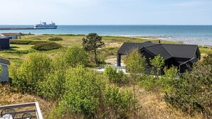 A coastal property with a view of the sea, a ship in the distance, and a small building with a sloped roof. - "Frender" - 150m from the sea by Interhome (Læsø)