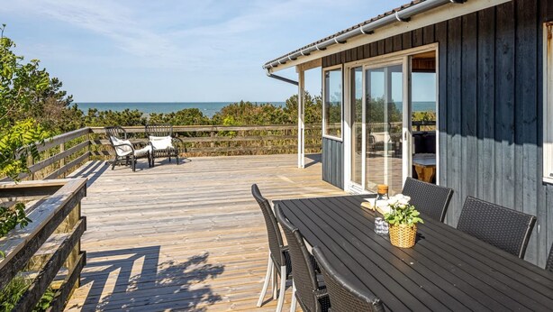 A wooden deck with outdoor furniture, a glass-enclosed patio, and a view of the ocean. - "Frender" - 150m from the sea by Interhome (Læsø)