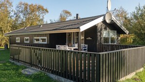 A wooden cabin with a fenced deck, a satellite dish, and a small porch area.