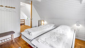 A bedroom with two beds, a wooden bench, a hanging light fixture, and a white door. - "Alkil" - 1.7km from the sea by Interhome (Ulfborg)