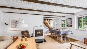A cozy living room with a fireplace, wooden beams, a dining area, and a staircase leading upstairs. - "Alkil" - 1.7km from the sea by Interhome (Ulfborg)