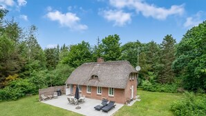 A thatched-roof house with a patio area, surrounded by a lush green garden. - "Alkil" - 1.7km from the sea by Interhome (Ulfborg)