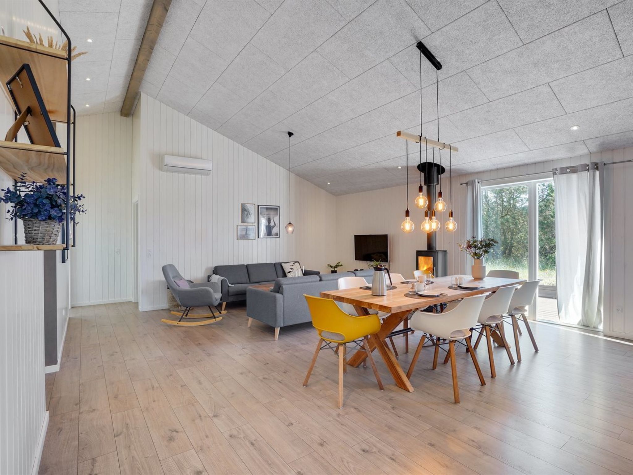 Un salon moderne avec un coin repas, comprenant une cheminée, un ensemble de canapés et une table à manger avec des chaises.