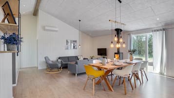 En moderne stue med spiseplads, der indeholder en pejs, en sofa og et spisebord med stole.