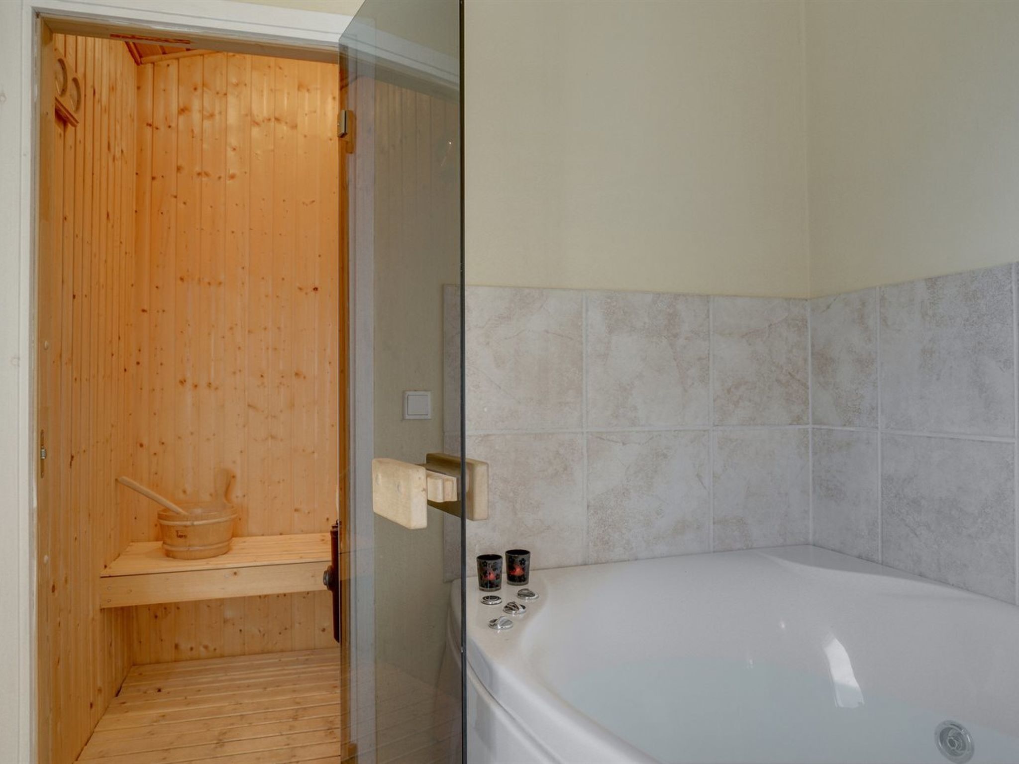 Un sauna avec un intérieur en bois et un espace douche séparé, délimité par des parois en verre, comprenant une baignoire blanche.