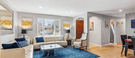 A spacious living room with a sofa, coffee table, and a dining area with chairs and a table.