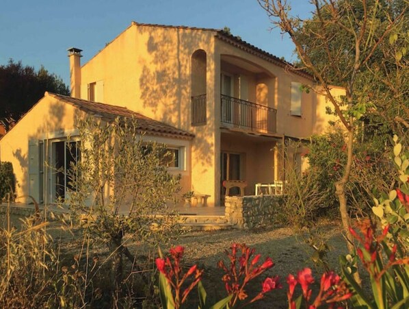 Stunning two-story residence with a flat roof and balcony, featuring a simple design and a charming garden.